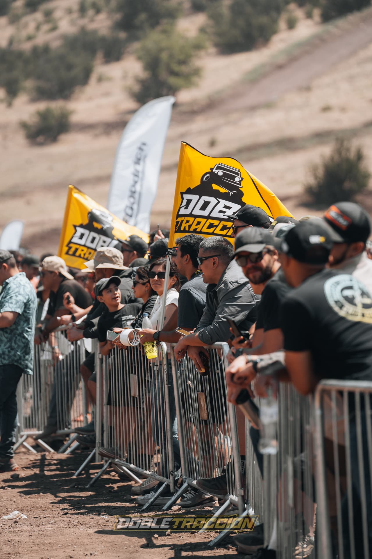 Banderas DOBLETRACCION y público en las vallas